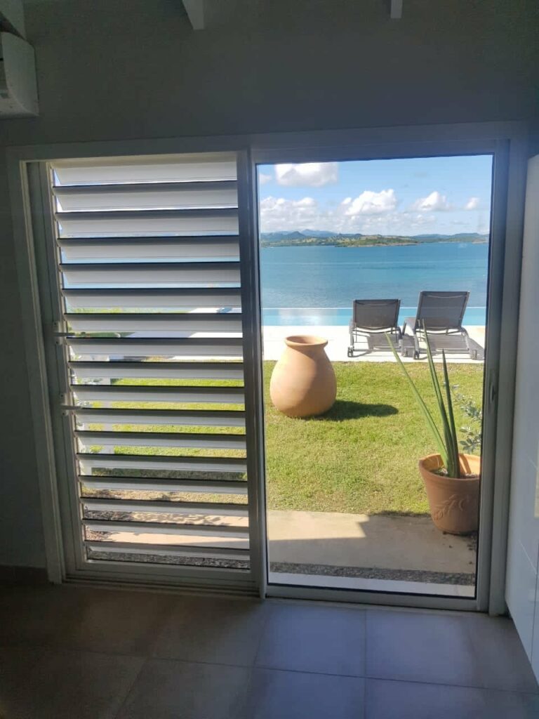 Baie coulissante alu blanc cuisine bois vue piscine infinity et mer — Pose 24 Martinique