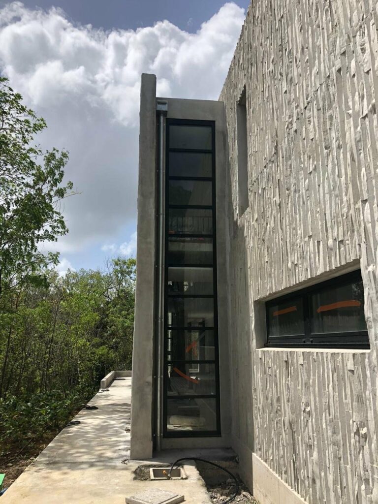 Longue fenêtre alu noir niche étroite façade béton brut chantier maison créole — Pose 24 Martinique