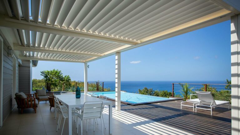Pergola bioclimatique blanche lames orientables terrasse vue mer et piscine — Pose 24 Martinique