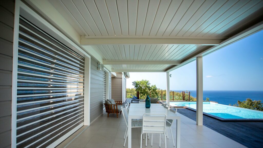 Sous pergola bioclimatique blanche table et piscine infinity vue mer — Pose 24 Martinique
